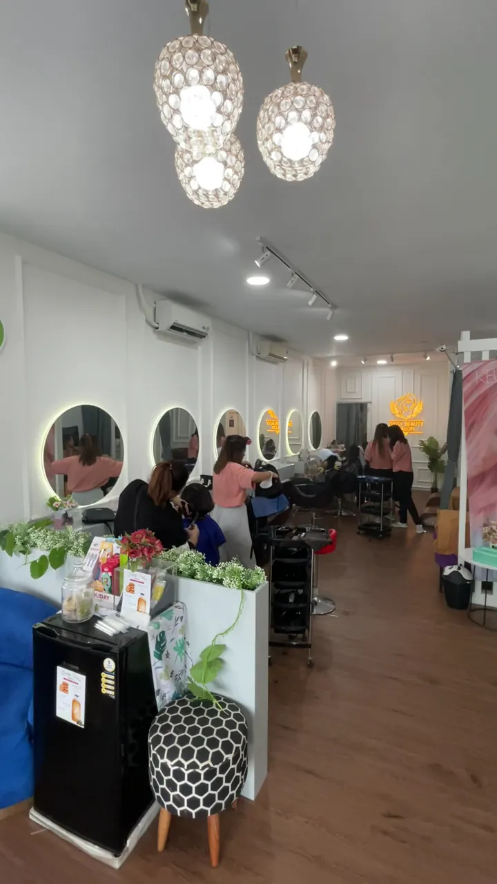 Tim dan pelanggan di ruang salon dengan tulisan Daisy Beauty Salon di dinding belakang